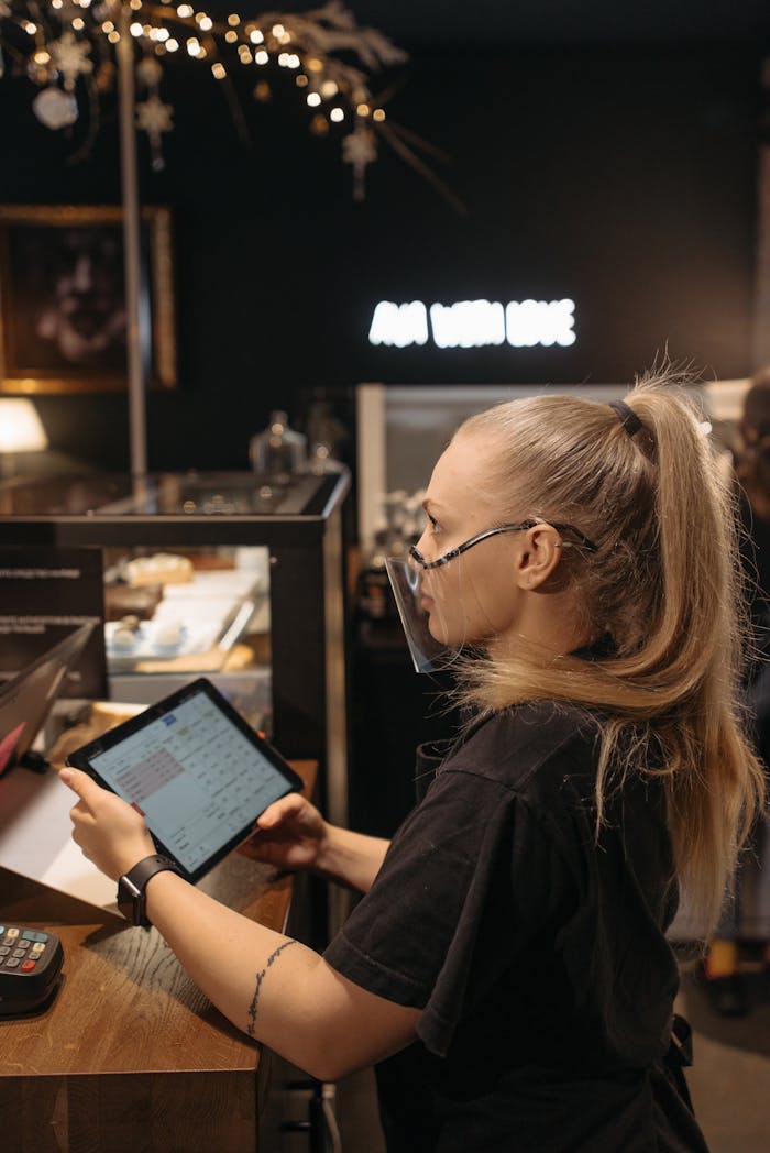 Barista at café counter using tablet, capturing the essence of modern coffee shop work atmosphere.